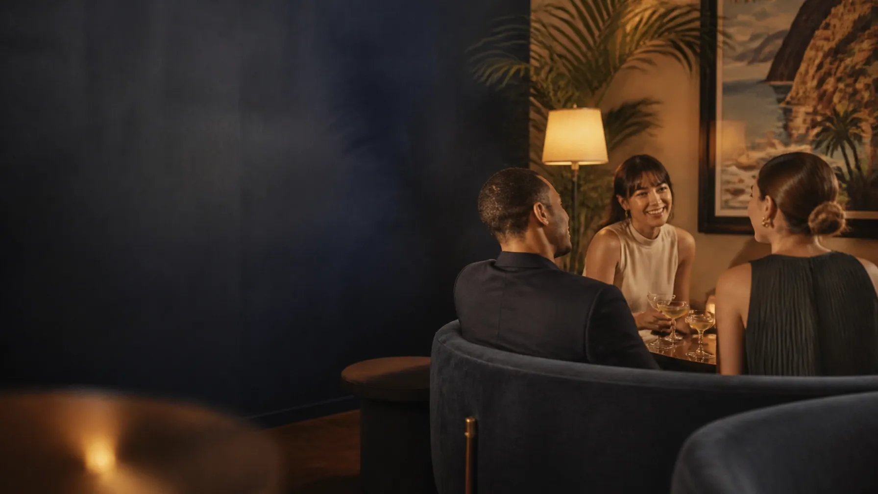 Adult friends smiling and talking together around a warmly lit table at an intimate social gathering
